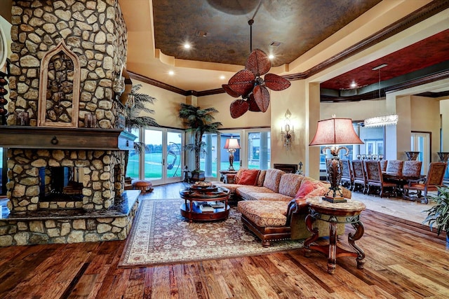 living room featuring ceiling fan, a high ceiling, a fireplace, wood finished floors, and crown molding