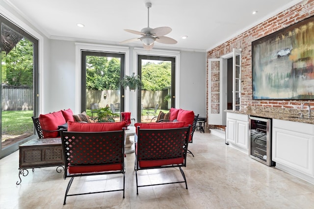 sunroom with beverage cooler, ceiling fan, a sink, and bar