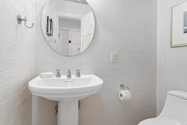 half bathroom featuring tile walls and toilet