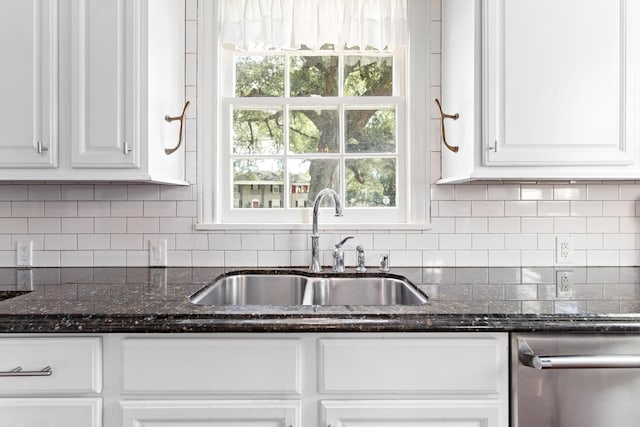 kitchen with tasteful backsplash, dark stone countertops, a sink, and white cabinets