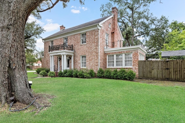 view of front of home with a chimney, fence, a front lawn, and brick siding