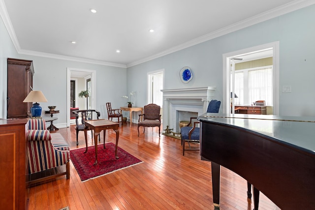 living area featuring crown molding, a fireplace, recessed lighting, baseboards, and hardwood / wood-style flooring