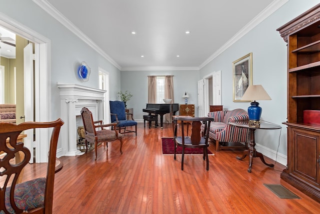 sitting room featuring crown molding, a fireplace, light wood finished floors, visible vents, and baseboards