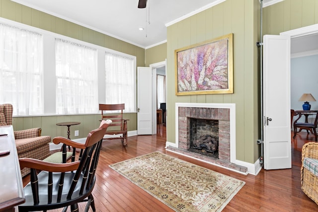 sitting room with ornamental molding, a brick fireplace, baseboards, and hardwood / wood-style floors