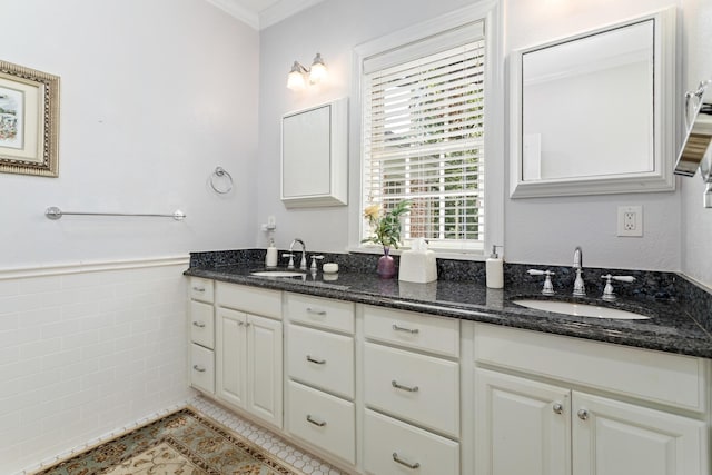 bathroom featuring double vanity, a wainscoted wall, tile walls, and a sink