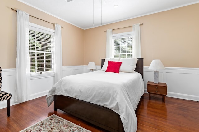 bedroom featuring a wainscoted wall, wood finished floors, and crown molding