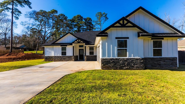 view of front of property featuring a front lawn, stone siding, board and batten siding, and driveway