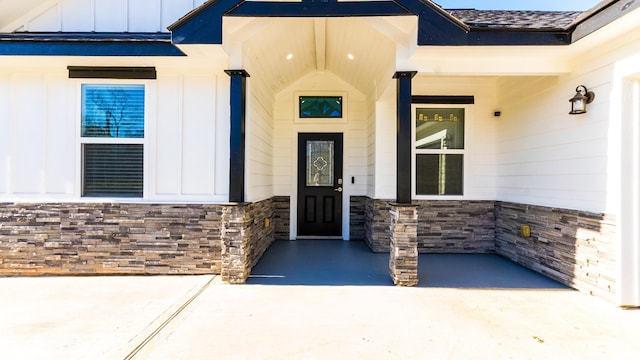 view of exterior entry featuring stone siding and board and batten siding