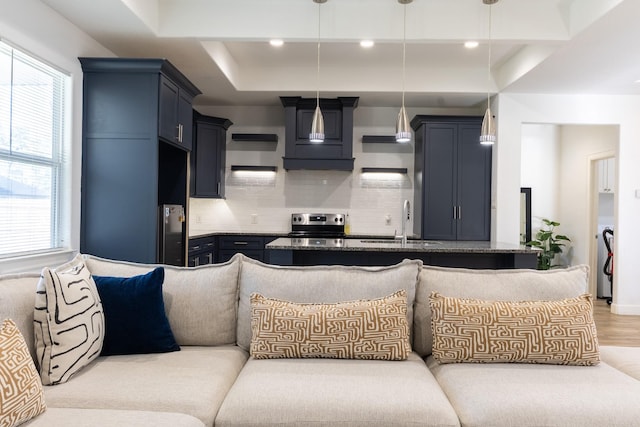 kitchen with backsplash, wood finished floors, hanging light fixtures, refrigerator, and a sink