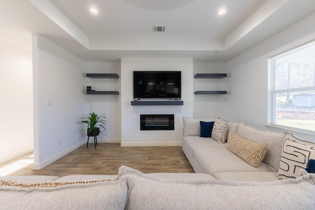 living room with visible vents, wood finished floors, a glass covered fireplace, recessed lighting, and baseboards