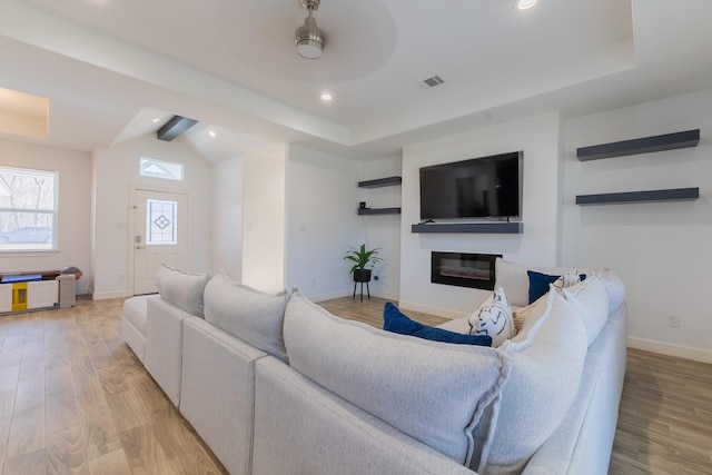 living room with a glass covered fireplace, light wood-style flooring, baseboards, and visible vents