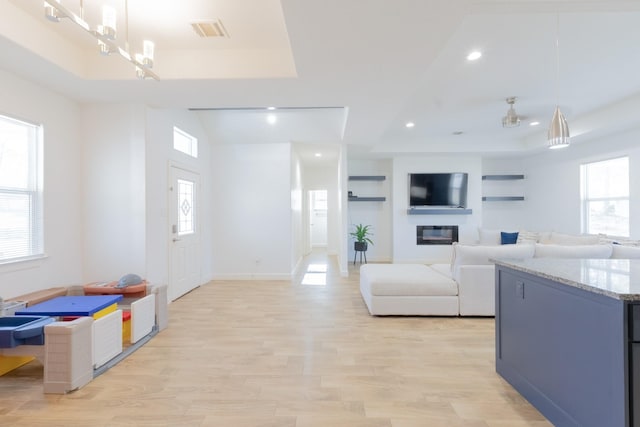 interior space featuring a tray ceiling, recessed lighting, visible vents, and light wood-type flooring