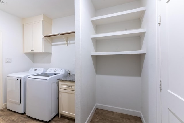 clothes washing area with visible vents, baseboards, washer and dryer, wood finished floors, and cabinet space