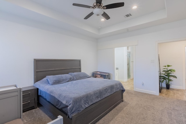 carpeted bedroom featuring a ceiling fan, visible vents, baseboards, recessed lighting, and a raised ceiling