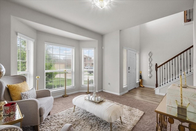 living area with baseboards, stairway, wood finished floors, and a healthy amount of sunlight