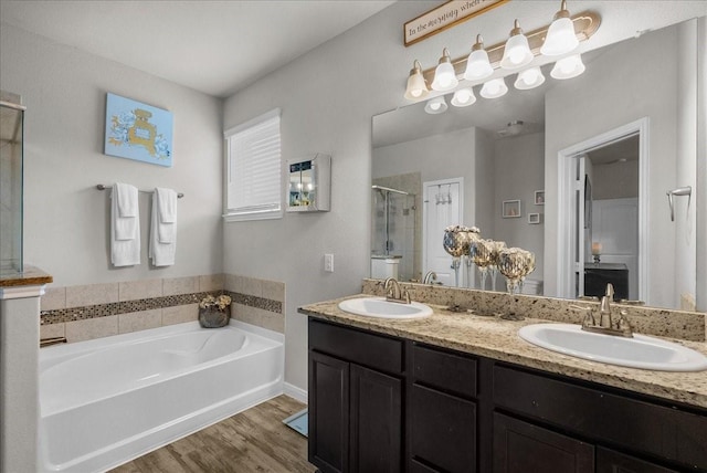 bathroom featuring a garden tub, wood finished floors, a sink, and a shower stall