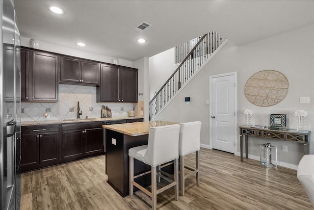 kitchen with light wood-style floors, a sink, visible vents, and a kitchen breakfast bar