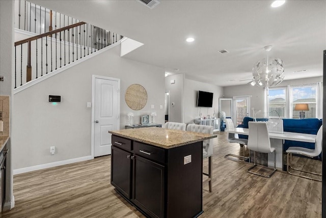 kitchen with baseboards, a kitchen island, a breakfast bar, open floor plan, and light wood-type flooring