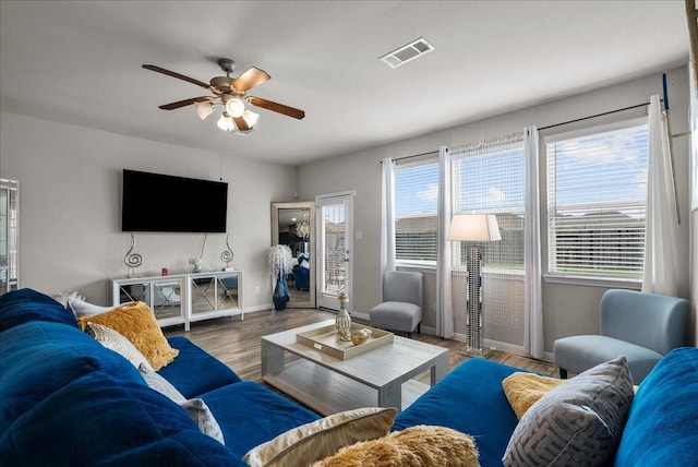 living area with baseboards, wood finished floors, visible vents, and a healthy amount of sunlight