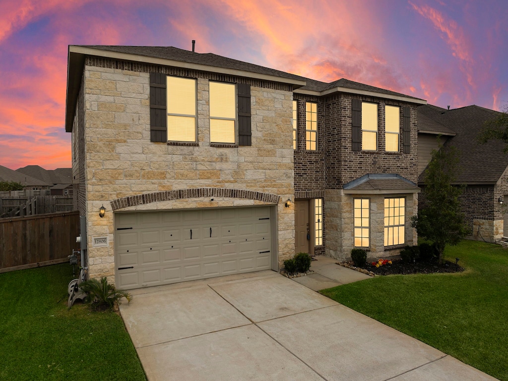 view of front facade with a garage, fence, stone siding, concrete driveway, and a front yard