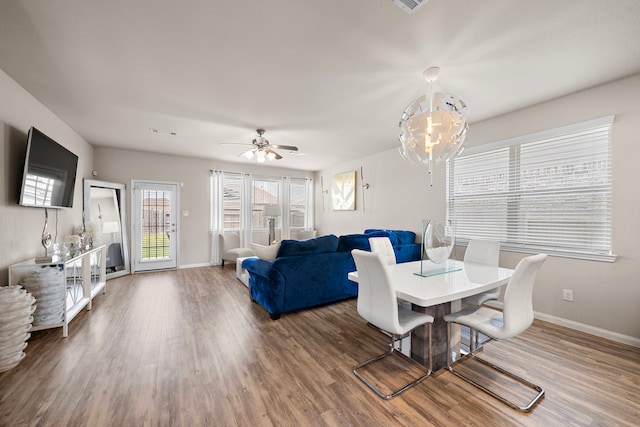 dining area with ceiling fan with notable chandelier, wood finished floors, and baseboards