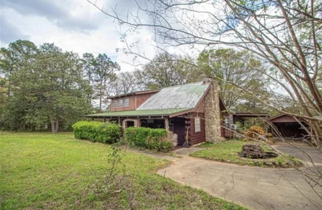 view of front of home with a carport, a front lawn, concrete driveway, and log siding