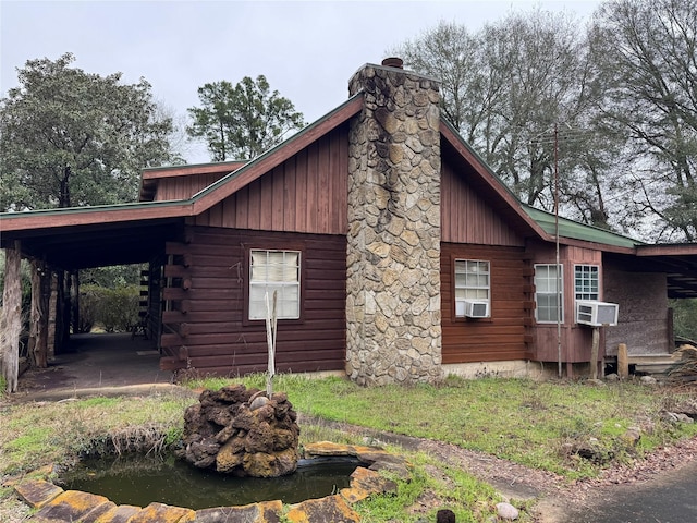 view of home's exterior with a chimney, cooling unit, and log exterior