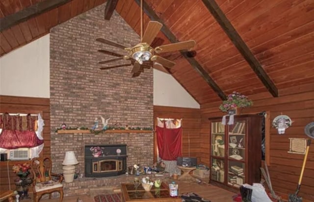 unfurnished living room featuring beam ceiling, wooden ceiling, wood walls, and a wood stove