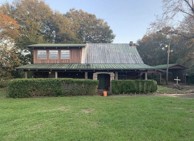 view of front facade featuring metal roof, a front lawn, and a chimney