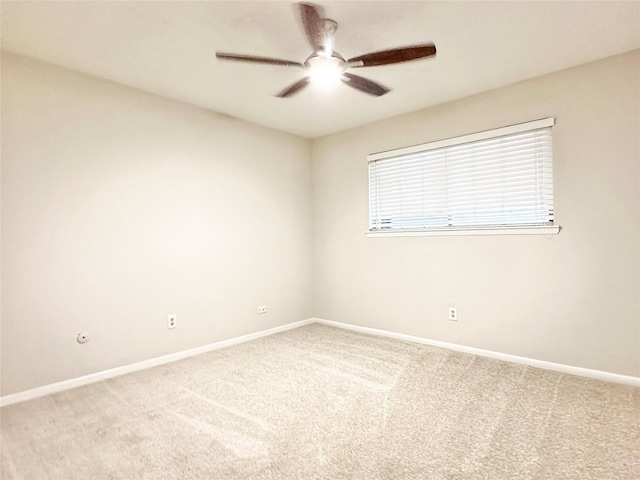 carpeted empty room featuring ceiling fan and baseboards