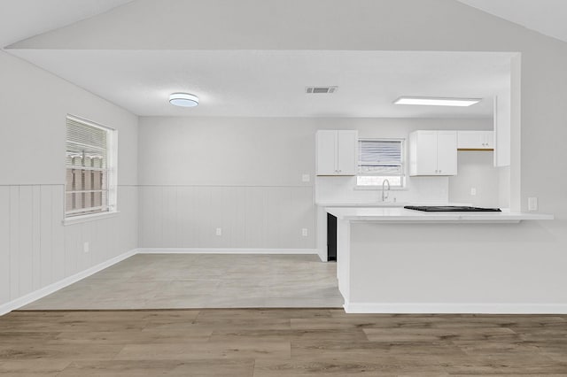 kitchen featuring a sink, visible vents, white cabinetry, light countertops, and light wood finished floors