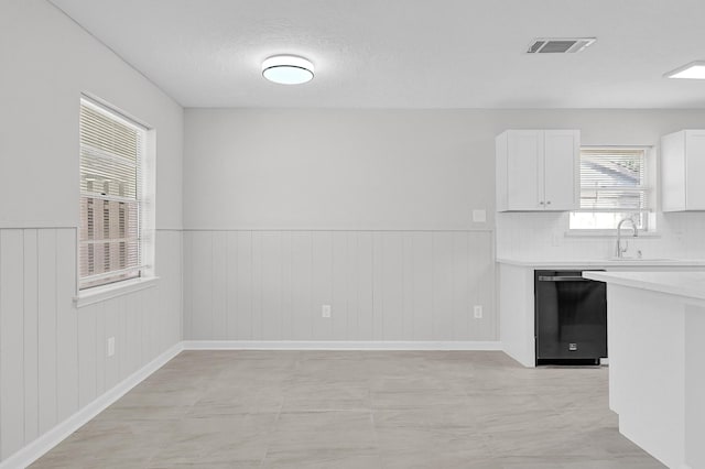 kitchen with a sink, visible vents, white cabinetry, light countertops, and dishwasher