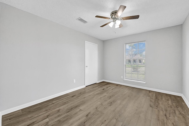 spare room featuring a ceiling fan, wood finished floors, visible vents, and baseboards