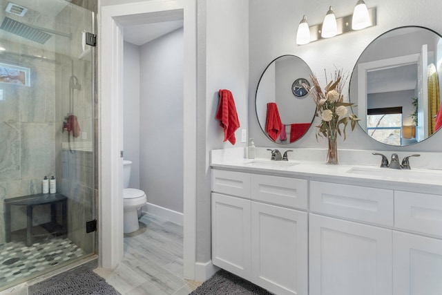 bathroom featuring toilet, a stall shower, and a sink