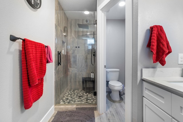 bathroom featuring toilet, a stall shower, wood finished floors, and vanity