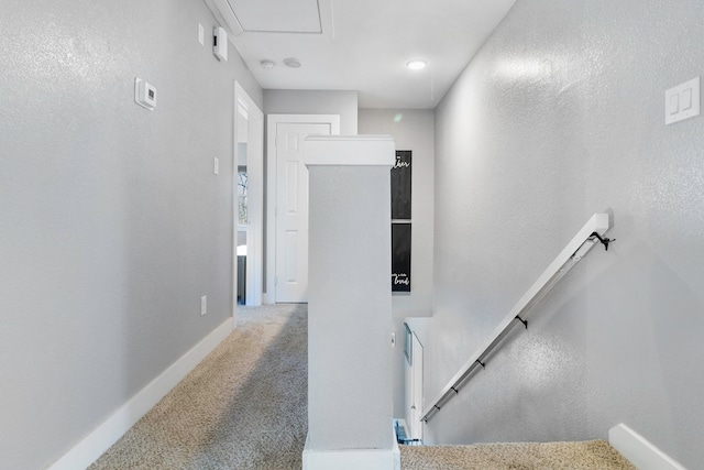 hallway featuring carpet, baseboards, and an upstairs landing