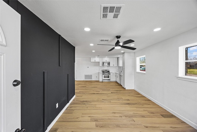 interior space with visible vents, appliances with stainless steel finishes, white cabinets, and decorative backsplash