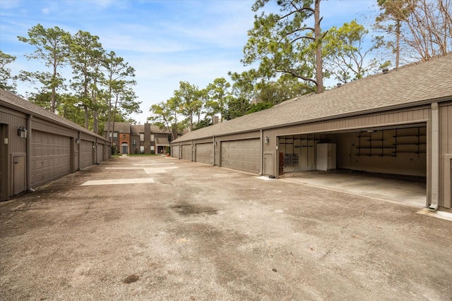 exterior space featuring roof with shingles and community garages