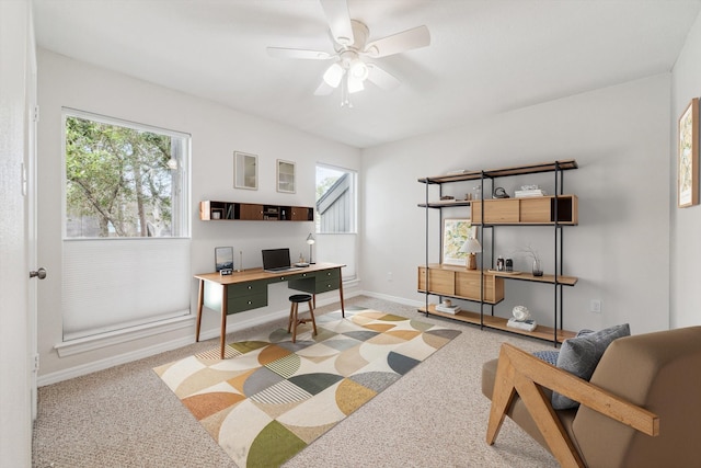 carpeted home office with ceiling fan and baseboards