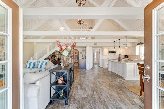 living room with light wood finished floors, arched walkways, lofted ceiling with beams, wooden ceiling, and an inviting chandelier