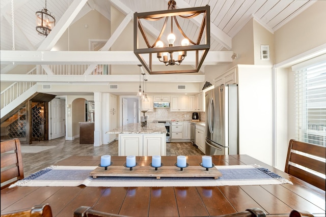 interior space with arched walkways, appliances with stainless steel finishes, a center island, and a notable chandelier