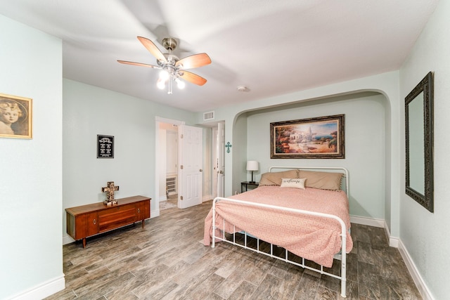 bedroom featuring baseboards, visible vents, a ceiling fan, arched walkways, and wood finished floors