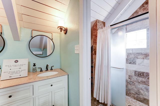 bathroom with lofted ceiling, a textured wall, a shower stall, and vanity