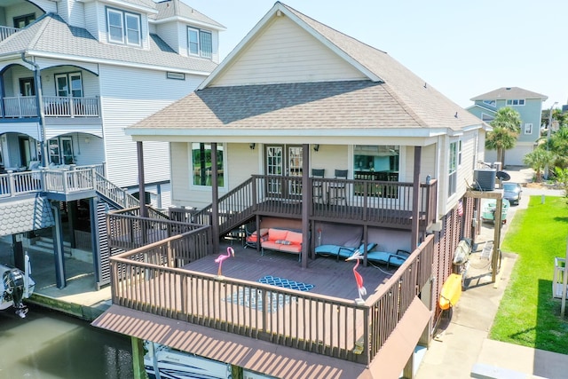 back of property featuring a shingled roof and stairway