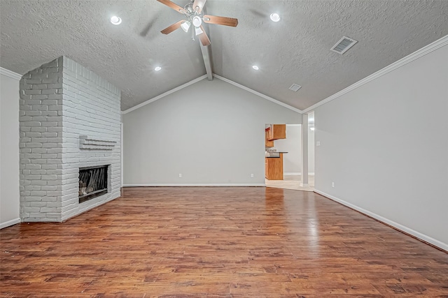 unfurnished living room with lofted ceiling with beams, a brick fireplace, visible vents, and wood finished floors