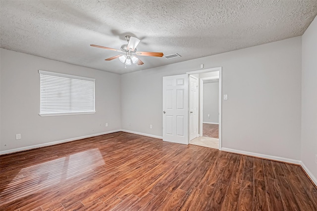 unfurnished room with baseboards, visible vents, ceiling fan, wood finished floors, and a textured ceiling