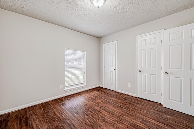 unfurnished bedroom featuring a textured ceiling, dark wood finished floors, and baseboards