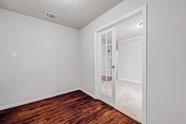 spare room with baseboards, visible vents, wood finished floors, a textured ceiling, and french doors