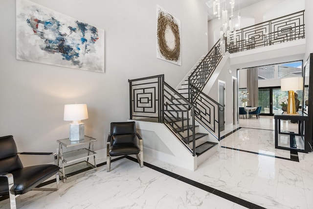 interior space featuring marble finish floor, stairway, and a notable chandelier