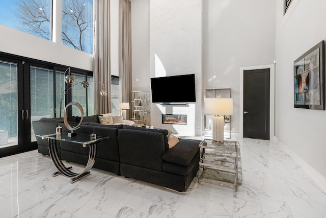 living area with baseboards, marble finish floor, a glass covered fireplace, and a healthy amount of sunlight